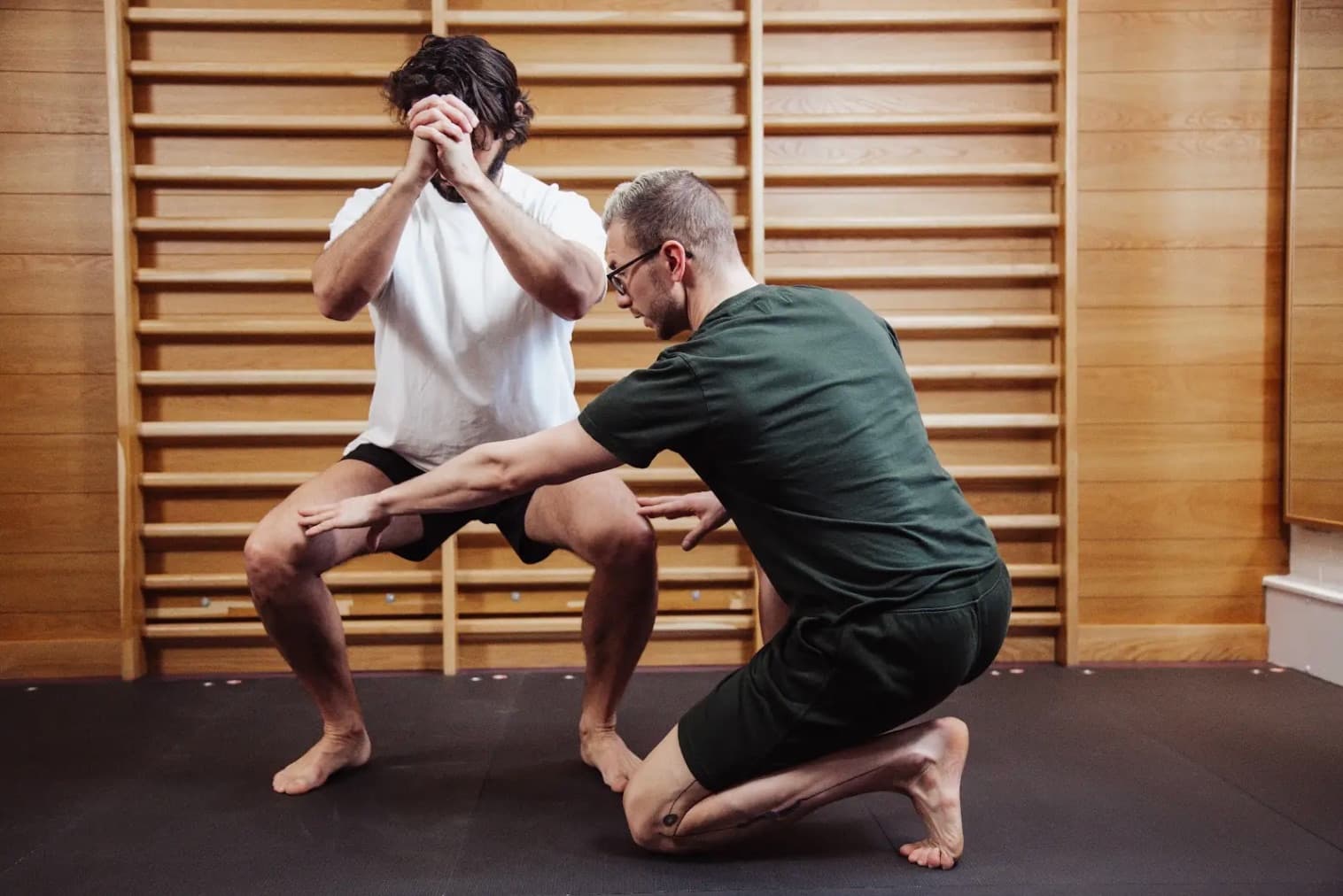 Physiotherapist guiding a client through a squat against the wall bars at SF Studios, Hampstead
