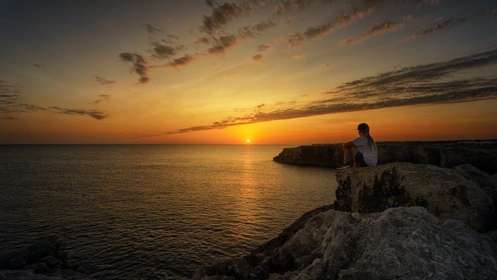 girl sitting on edge looking at sunset