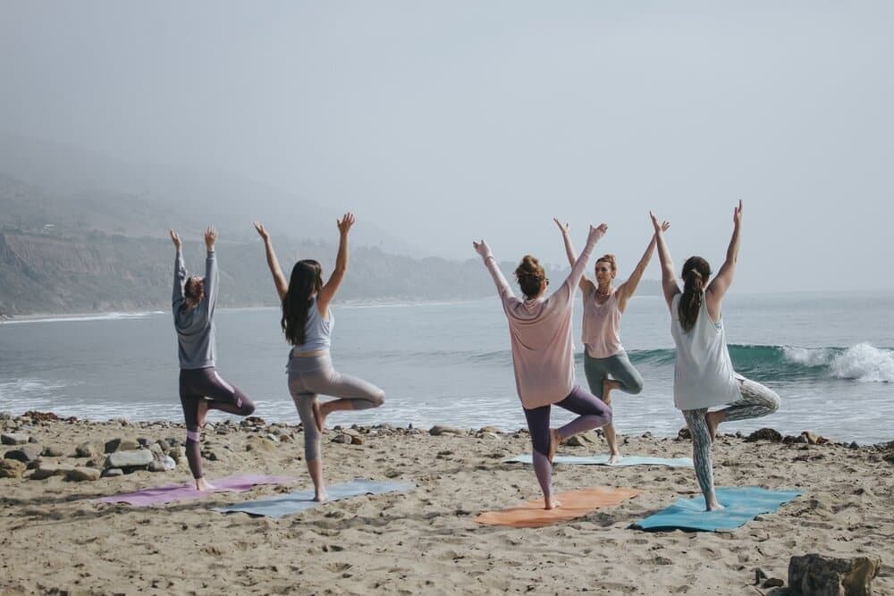 ladies doing yoga on the beach